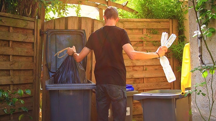 man throwing out garbage and sorting recyclables