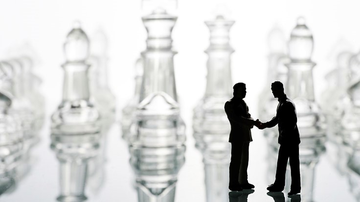 shaking hands infront of chess board