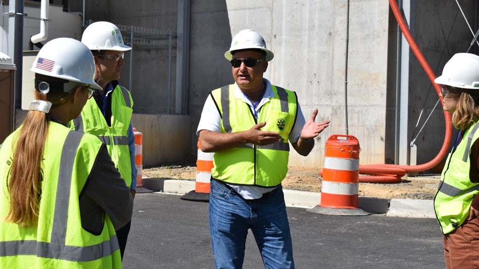 Man in hard hat gives tour outside a facility