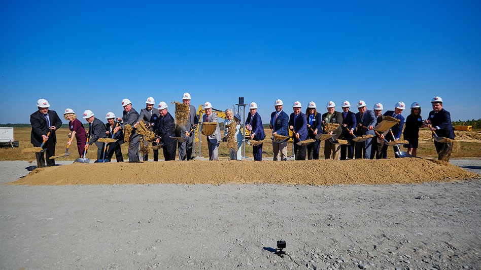 people in hard hats with shovels of dirt in front of a blue sky