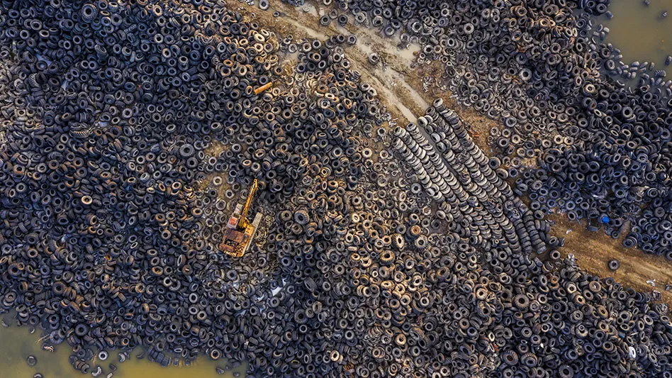 Aerial view of excavators sorting tires in a large dump yard