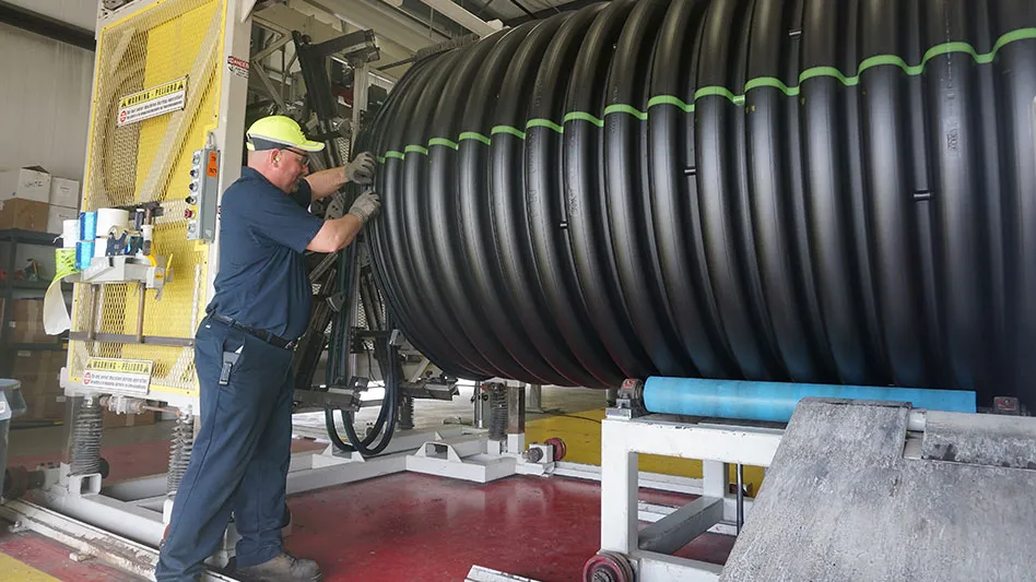 an ads employee adds a gasket to a large black corrugated pipe