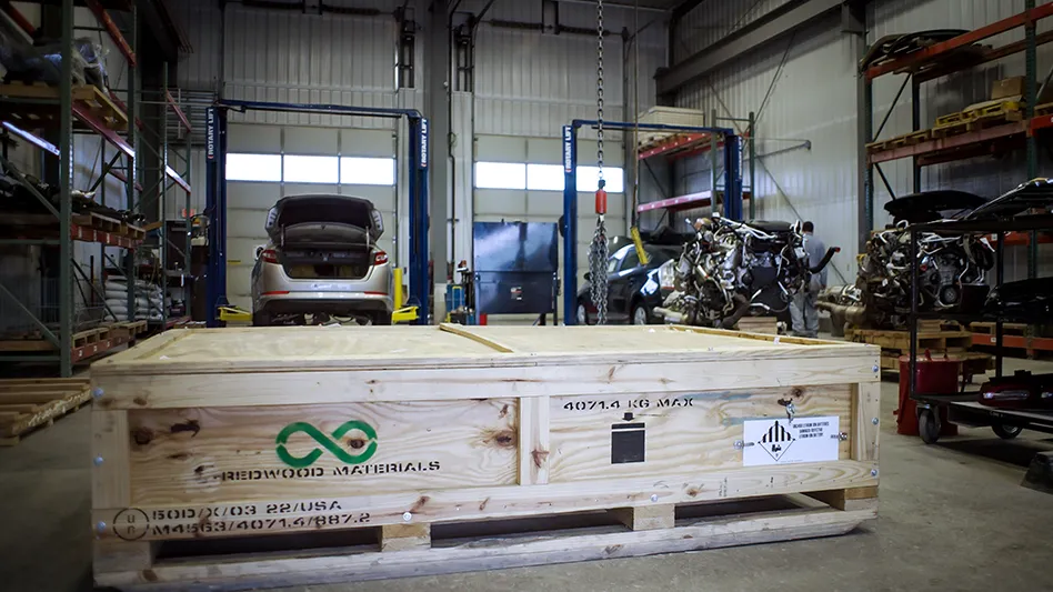 A wooden container issued by Redwood Materials is set to house an electric vehicle battery for transportation to a recycling facility.