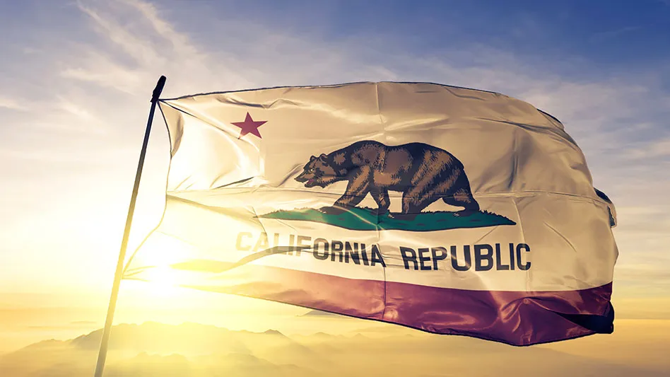 California flag flying against a blue and golden sky with the sun in the background
