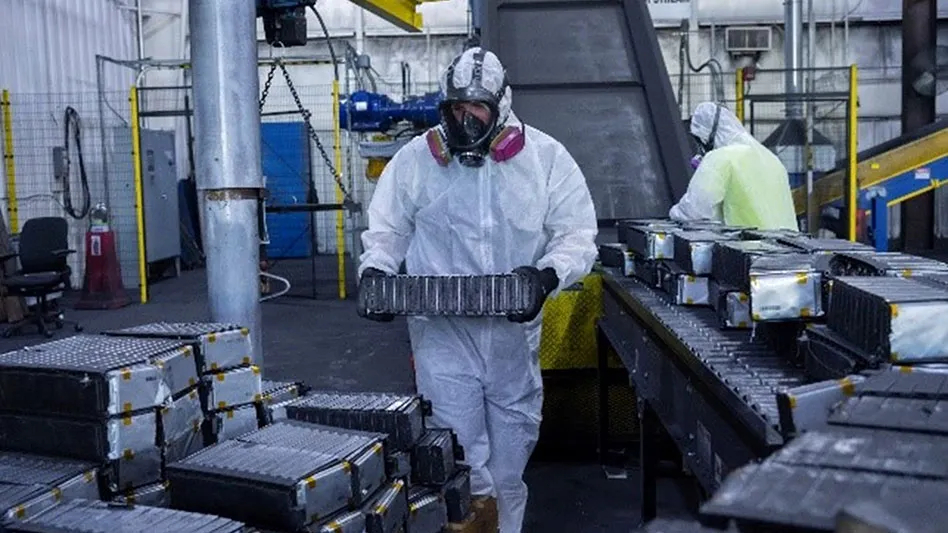 a man in a white protective suit carries lithium-ion batteries for recycling