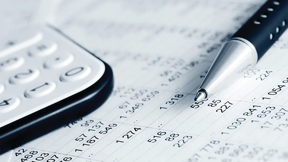 A closeup of a calculator, financial reports and a pen.
