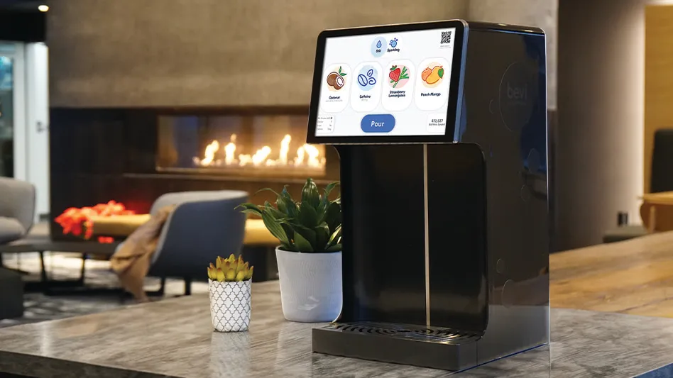 A black Bevi smart water cooler sitting on a countertop in a hotel's common area.