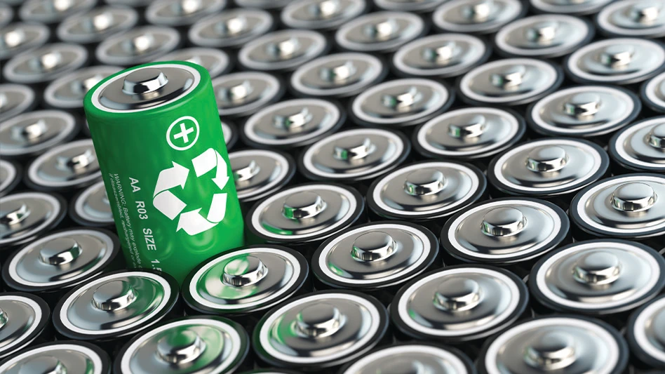A lone green battery with a recycling symbol on it rises above a pile of similar batteries.