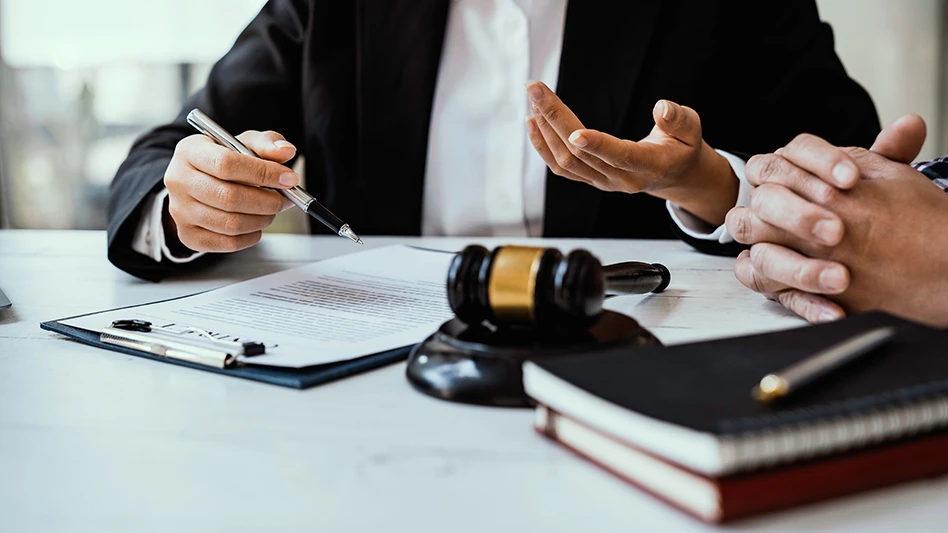 a man holding a pen sitting at a table with papers and a gavel