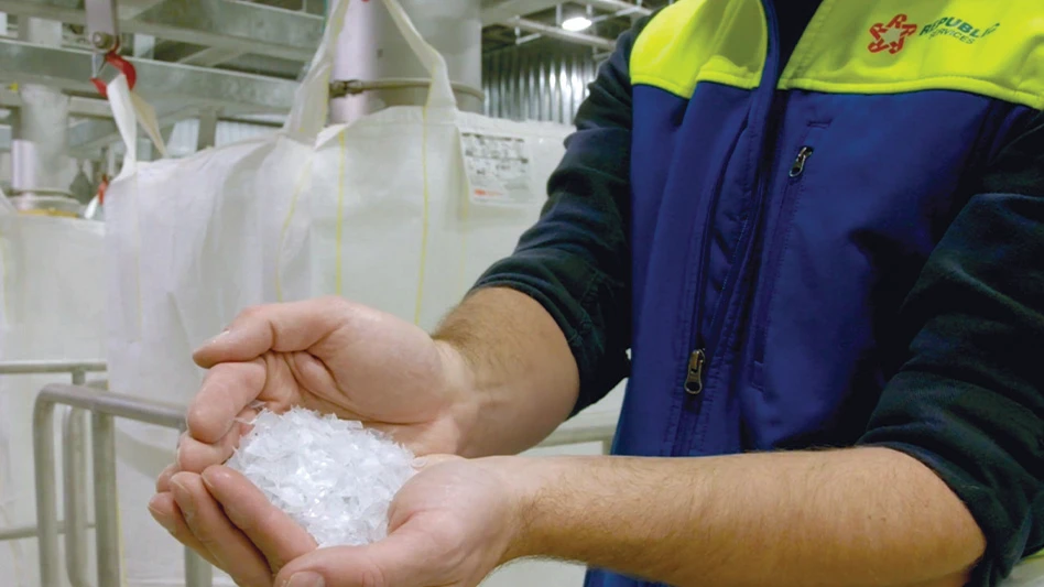 A hand holds recycled PET flake produced at a plastic recycling facility.