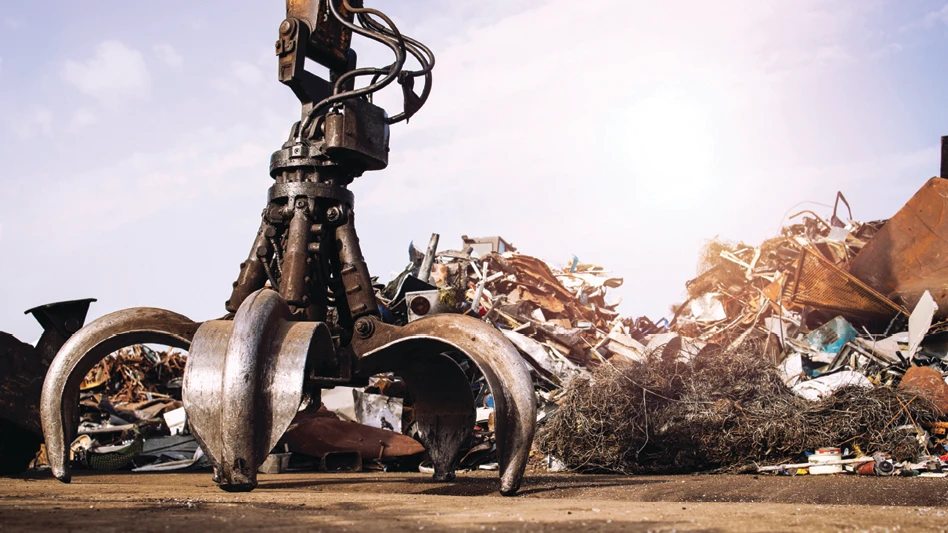 A grapple sits on the ground at a scrapyard.