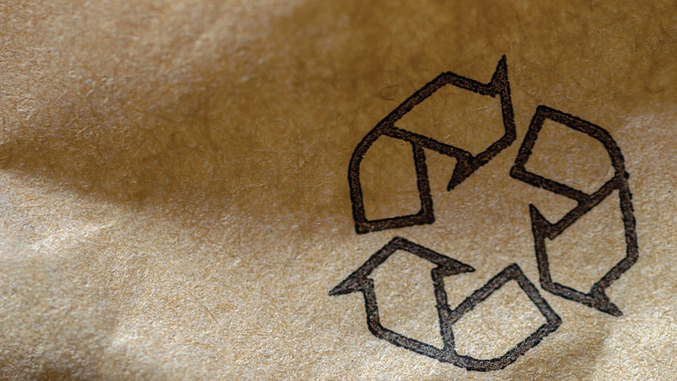 A closeup of a printed recycling symbol on a piece of paper packaging.