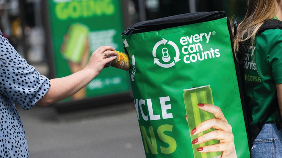 A person places an aluminum can in a deposit bin.