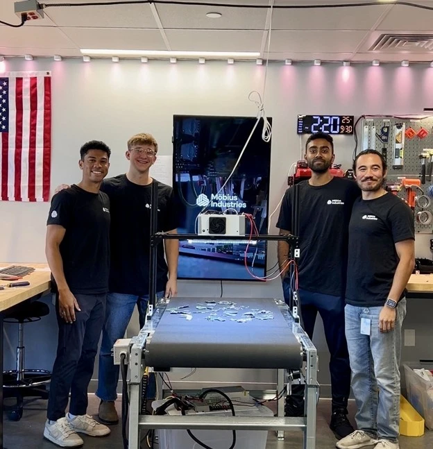 four men stand before a machine