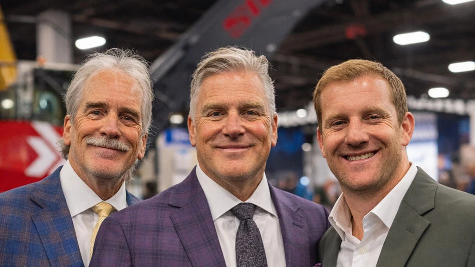 three men in jackets stand in fromt of a Sierra machine