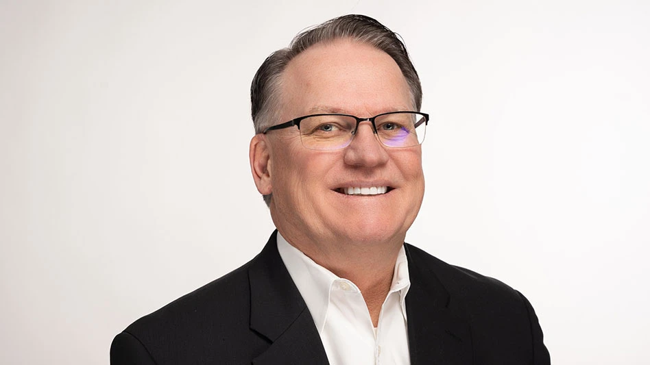 a smiling man wearing glasses and a black suit jacket with a white button-up underneath