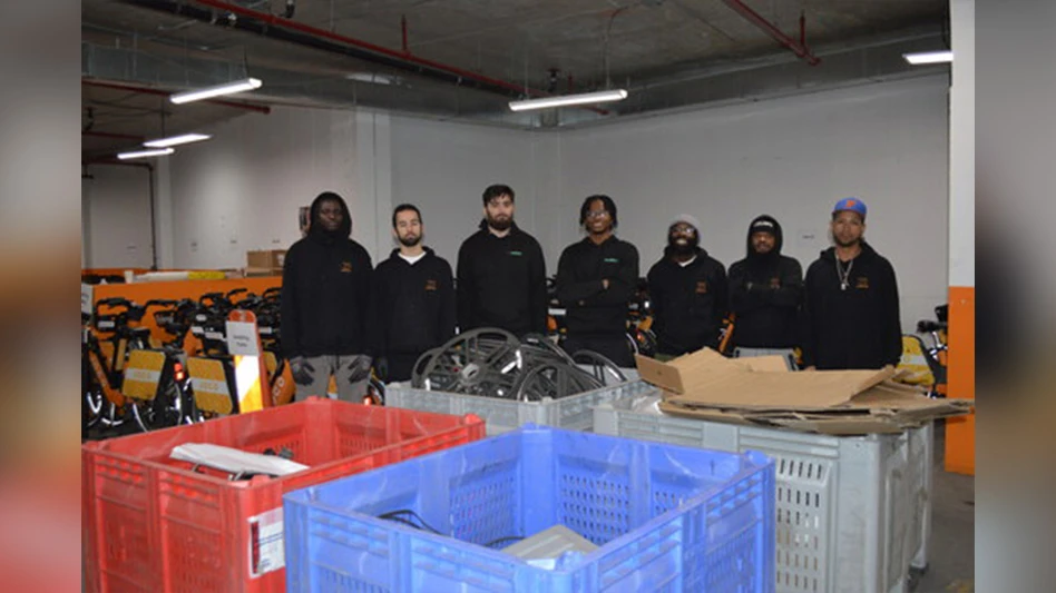 group of people standing in front of recycling bins