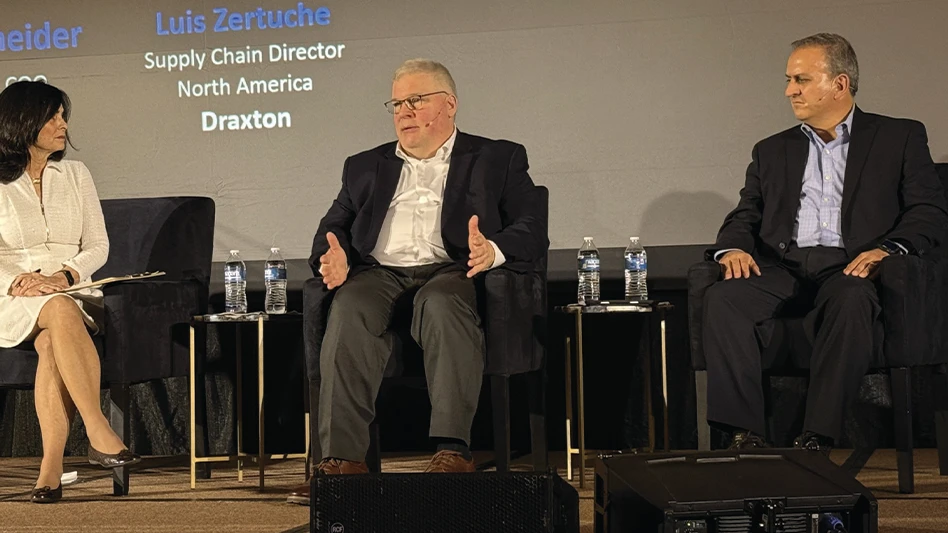 Three people sit and talk on a stage during a conference.