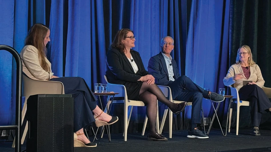 Four people sit on a stage at a conference.