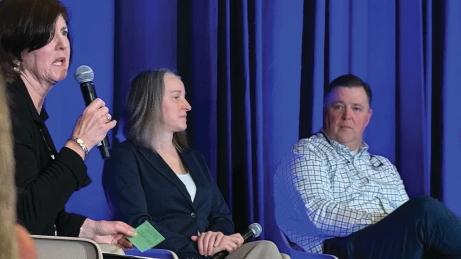 Three people sit on a stage and speak during a conference.