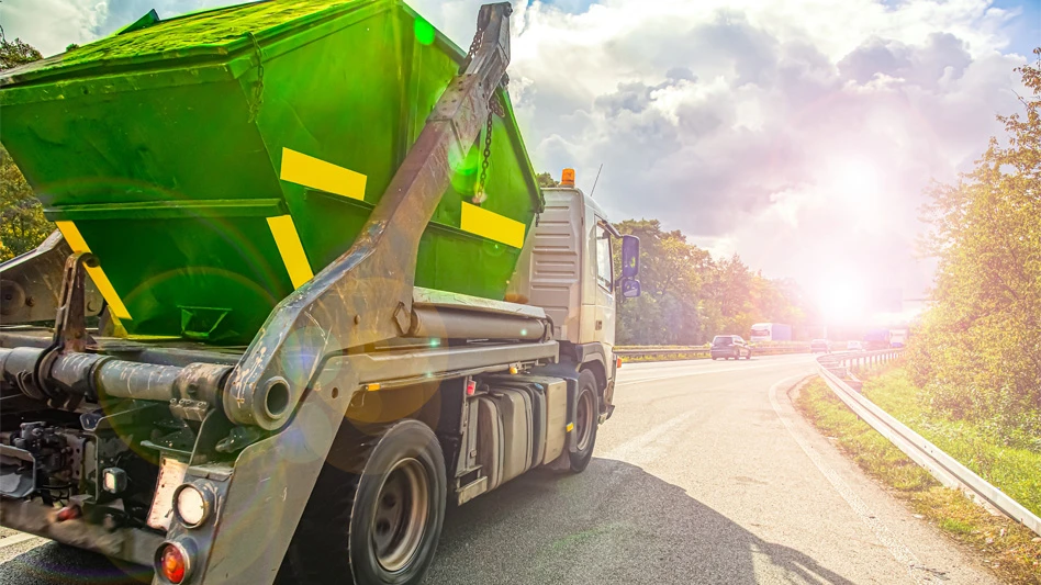 rear view of green refuse truck driving